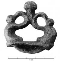 AJG-3005 - Anneau de jougbronzeTPQ : -100 - TAQ : 1Anneau de joug en fonte creuse, à décor plastique, composé de deux motifs en S adossés et surmontés par un bouton strié et émaillé ; stries pour émail également sur les boutons latéraux ; forte bélière en dessous.