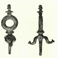 AJG-4034 - Anneau de jougbronzeForte cheville sommée d'un anneau passe-guide, surmonté d'un élément en balustre et orné à sa base de deux larges feuilles renflées à extrémité bouletée.