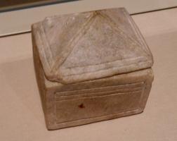 BTE-9003 - Boîte ou reliquairealbâtreTPQ : 1100 - TAQ : 1200Boîte parallélépipédique, taillée dans un bloc d'albâtre, avec un décor de filets sur les côtés; le couvercle simplement posé sur une feuillure est en forme de toiture à quatre rampants.