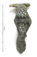 FIB-41405 - Fibule émailléebronzeTPQ : 70 - TAQ : 100Fibule à charnière dont le corps losangique est formé de deux triangles accolés par leur base, avec chacun 4 lignes de petits triangles émaillés (10 à 12 logettes au total). Pied en tête de reptile stylisée.