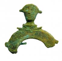 FIB-4167 - Fibule en forme de pelte avec têtebronzeTPQ : 50 - TAQ : 200Fibule en forme de croissant ou de pelte, pointes en bas, étamée : une tête humaine de face, de style gaulois et posée sur quelques moulures, surmonte le croissant inversé.