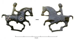 FIB-4341 - Fibule zoomorphe, groupe : cavalierbronzeTPQ : 100 - TAQ : 150Cheval au galop harnaché et monté par un cavalier ; corps émaillé de disque et de pastilles rondes; barre de sol.