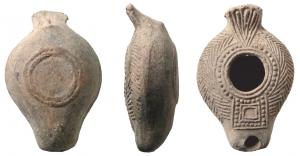 LMP-41092 - Lampeterre cuiteAnse en évantail strié. Réservoir piriforme de profil biconvexe. Bandeau portant deux grandes palmes. Grand trou d'alimentation bordé par une frise de globules. Bec au bout rectiligne; un carré au départ orné d'une frise de globules. Base limitée par deux fins bourrelets concentriques.