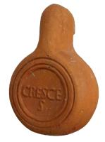 LMP-41913 - Lampe de firme : CRESCES terre cuiteTPQ : 50 - TAQ : 100Lampe moulée sans anse: le réservoir circulaire est de profil biconvexe asymétrique; bandeau penché vers l'extérieur portant deux ou trois tenons rectangulaires non percés, sur l'axe horizontal. Disque en cuvette profonde bordée par un bourrelet continu. Bec long au petit canal non communiquant avec le disque, chanfreiné sur les côtés. Base circulaire plate en creux limitée par deux anneaux concentriques enfermant l'estampille moulée CRESCES en relief. 