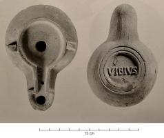 LMP-42060 - Lampe de firme : VIBIVSterre cuiteTPQ : 100 - TAQ : 200Lampe moulée, sans anse. Réservoir circulaire de profil biconvexe asymétrique. Bandeau penché vers l'extérieur porte trois tenons rectangulaires percés, disposés en triangle. Disque en cuvette profond bordée par un bourrelet continu. Bec long au méplat en forme de pelle, porte un canal étroit. Deux sillons soulignent le départ. Trou d'évent sur le disque et le bec. Base circulaire plate limitée par deux anneaux concentriques porte la marque VIBIVS, ou VIBIVS / F, en relief.