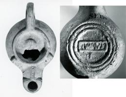 LMP-42501 - Lampe de firme : QVANVSterre cuiteTPQ : 50 - TAQ : 100Lampe moulée de type Firmalampe, ansée ; deux ergots, disque plat orné d'un masque ; sous le fond, marque QVANVS en relief, dans un cadre rectangulaire également en relief ; symbole dessous.