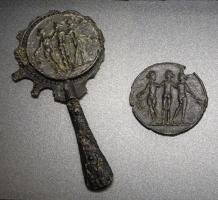 MRR-4080 - Miroir en verre, cadre en plombplomb, verreMiroir en verre, bordure circulaire en plomb découpée en festons, manche coulé en forme de massue d'Hercule, avec nodosités; au revers, médaillon moulé figuratif : Aigle romaine; les Trois Grâces, amphore ...