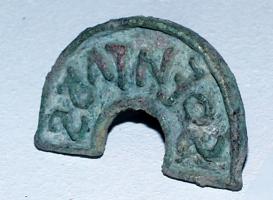 SIG-4012 - Signaculum en demi-cerclebronzeTPQ : 1 - TAQ : 400Signaculum (cachet) en demi-cercle, formant une estampille encadrée d'un cadre également arqué; lettres en relief et inscription rétrograde; anneau de suspension au revers.