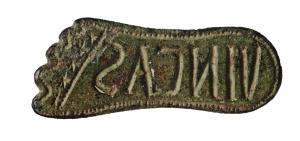 SIG-4084 - Signaculum in planta pedis (lettres latines)bronzeTPQ : 250 - TAQ : 400Sceau-matrice en forme de pied ou de semelle de chaussure, comportant des lettres en creux formant une inscription non rétrograde sur une ou deux lignes, sans cadre, destinée à être imprimée sur un matériau meuble. Ces signacula ont généralement un anneau mince, sans contre-sceau.