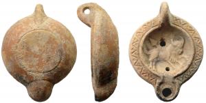 LMP-41686 - Lampe africaine à canal : Taureau et lanceterre cuiteTPQ : 225 - TAQ : 275Lampe moulée, anse verticale, percée, guillochée sur la tranche. Réservoir circulaire de profil biconvexe. Bandeau penché vers l'extérieur décoré d'un chevron orné de petits cercles en creux. Disque en simple cuvette profonde limitée par un bourrelet qui borde un étroit canal et entoure le méplat du bec. Taureau à droite transpercé par une lance. Petit bec arrondi. Base circulaire plate  limitée par un sillon.  Engobe ocre rouge.  
