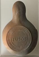 LMP-42468 - Lampe de firme : PRISCVSterre cuiteTPQ : 50 - TAQ : 200Lampe moulée sans anse: le réservoir circulaire est de profil biconvexe asymétrique; bandeau penché vers l'extérieur portant deux ou trois tenons rectangulaires sur l'axe horizontal. Disque en cuvette profonde bordée par un bourrelet continu. Bec long au petit canal non communiquant avec le disque, chanfreiné sur les côtés. Base circulaire plate en creux limitée par deux anneaux concentriques enfermant l'estampille moulée PRISCVS, en relief. 
