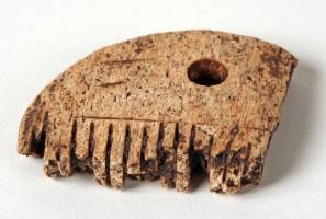PGN-3002 - Peigne monobloc en os à une rangée de dents et sommet arrondiosPeigne en os (ou bois de cerf) à une rangée de dents, dos arqué, percé d'un trou de suspension ; les côtés sont parfois encochés.