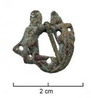 FER-7017 - Fermail figuratifbronzeTPQ : 1200 - TAQ : 1350Fermail figuré : homme (saint Michel ?) terrassant un dragon (sous l'aspect d'un crocodile), tenant le cou avec un main et la queue avec l'autre. Ou Hercule brandissant la peau du Lion de Némée.