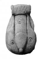 AMP-3003 - Amulette phalliqueosPendant sculpté en os, revers plat, figurant des parties génitales masculines sous une moulure horizontale sommairement hachurée pour figurée la pilosité, et percée transversalement pour la suspension; les proportions générales sont ramassées, avec un style schématique parfois accentué par la présence d'ocelles sur le pénis et les testicules.