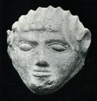 ANT-4009 - Antéfixe : tête de Satyreterre cuiteAntéfixe moulée, ornée en façade d'une tête masculine, aux traits stylisés, les cheveux tirés en arrière, sans palmette autour. Les yeux sont larges, mais vides; la bouche peut être légèrement surmontée d'une moustache, marquée par des incisions verticales.