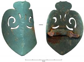 APJ-4006 - Applique de jougbronzeApplique en forme de pelte, repliée selon un axe longitudinal, et pourvue au revers d'un robuste anneau coulé en même temps que l'objet ; traces de fer.