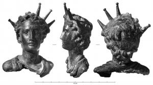 APM-4028 - Applique : buste de SolbronzeBuste de Sol, figuré sous la forme d'un jeune homme, aux traits idéalisés, vêtu d'une tunique dont on ne voit que l'encolure plissée; des rayons, parfois à extrémité bouletée, émergent de la chevelure et encadrent régulièrement le visage.