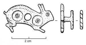 APT-4010 - Applique à tenons en T, type C4bronzeApplique pourvue au revers de 2 tenons en T, guillochés sur la partie extérieure de la barrette ; l'objet est percé transversalement et un anneau retenu par un crampon replié à l'arrière y jouait librement. Ce type représente un lièvre bondissant à droite, le corps marqué de deux disques d'émail rouge, avec le pelage indiqué par de fines incisions.