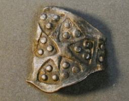 BAG-6002 - Bague VikingargentTPQ : 875 - TAQ : 950Bague en feuille mince, anneau très élargi du côté externe, recouvert de multiples empreintes d'un poinçon géométrique : 1 ou 3 points dans un cartouche triangulaire. Les extrémités effilées sont simplement nouées l'une sur l'autre.
