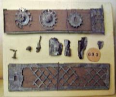 BTE-4004 - Boîtebois, bronzeBoîte allongée, sans doute de section renflée sur les longs côtés, comportant plusieurs cotés habillés de bronze. L'un d'eux est couvert d'une motif ajouré en résille, l'autre semble avoir été muni de simples glissières destinées à faciliter le coulissement d'un couvercle dans une feuillure. L'un des côtés était équipé de motifs circulaires ajourés.