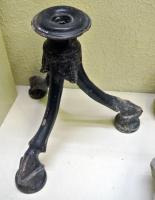 CDL-3003 - Candélabreterre cuiteCandélabre moulé, en terre cuite à vernis noir : trépied à sabots de capriné, posés sur des socles; au sommet, rondelle perforée, pour l'insertion d'une hampe (torche, chandelle ?)
