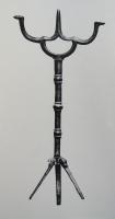 CHL-7002 - Chandelier pliantbronzeChandelier dont le piètement tripode se replie sur l'axe central pour faciliter le transport de l'objet, à courte hampe verticale, interrompue par une ou plusieurs bagues, et un sommet de forme variable : soit en étriers superposés formant trois éléments, pattes pour fixation de bougies (par enfoncement ?) autour d'une pique centrale; soit avec seulement les deux fixations latérales, sur un support en U; soit un élément de ce type associé à une douille; etc.