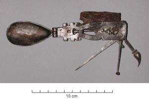 CNF-4055 - Ustensile pliant mutifonctionnelargentOutil composite, pliant, formé de six ustensiles articulés par des charnières sur un manche plat et ajouré : un cochlear à cuilleron en forme de goutte, un couteau, une sorte de trident, une pointe, une curette et un cure-dents foliacé.