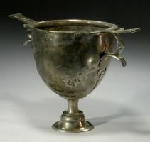 CPE-3009 - Coupe à pied, panse lisseargentCoupe à panse semi-ovoïde, pied tubulaire étranglé et support évasé; les deux anses sont constituées d'un poucier plat, appuyé sur un doigtier lui-même soutenu par un ergot prolongé par des appliques finement ajourées épousant le profil de la panse.