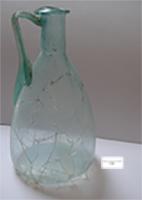 CRU-4077 - Cruche conique élancée AR 163.1verreCruche soufflée à la volée, à haute panse conique, fond plat et anse rubanée rattachée sous la lèvre et au sommet de la panse.