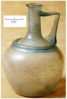 CRU-4123 - Cruche à ressaut à l'épaule Is. 53verreCruche en verre bleu-vert, soufflée à la volée, présentant une panse pommiforme décorée d'un anneau creux au niveau de l'épaulement. Fond plat, légèrement concave. Une anse rubanée appliquée sur le col et l'épaulement.