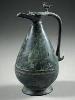CRU-6002 - Cruche à panse piriformebronzeCruche à panse renflée vers le bas (piriforme), col étranglé, bec verseur; anse en ore, surmontée d'une figurine de paon.