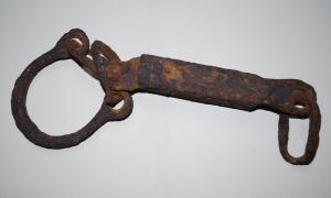 ENT-4011 - EntravesagateEntraves constituées d'un bloc-cadenas oblong, auquel se relient un (ou deux ?) anneaux ouverts associés à des anneaux allongés.