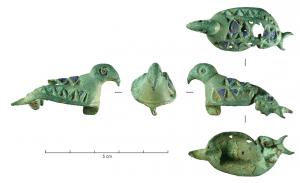 FIB-41266 - Fibule zoomorphe : oiseaubronzeLe corps du volatile est traité en ronde-bosse, avec un corps stylisé et en amande, couvert de logettes d'émail de forme triangulaire;  la tête est redressée, arrondie, avec un bec crochu :  l'aspect général est celui d'un petit rapace. Articulation à charnière, sur plaquettes.