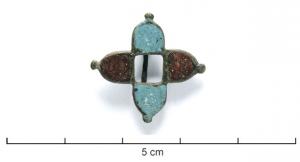 FIB-41349 - Fibule émailléebronzeFibule de composition cruciforme, formée de quatre parties en arc de cercles, émaillées de couleur contrastée deux à deux, autour d'un vide central; boutons aux pointes; au revers, articulation  charnière sur deux plaquettes.