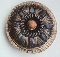 FIB-41400 - Fibule discoïdaleargentFibule circulaire non émaillée, pourvue d'une collerette découpée de fentes rayonnantes, avec les interalles occupés par des cabochons de verre coloré, et au centre un autre cabochon en pierre colorée ou en verre.