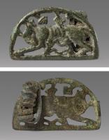 FIB-41770 - Fibule zoomorphe, groupe : Louve et JumeauxbronzeDans un cadre en demi-cercle, une louve debout vers la gauche allaite deux jumeaux se faisant face; au-dessus, feuilles de lierre; au revers, articulation à ressort sur axe, monté sur une plaquette coulée.