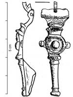 FIB-4443 - Fibule à protubérances latérales médianesbronzeFibule à protubérance latérales, pied lisse et tendu, terminé par un bouton; au lieu des traditionnelles moulures de l'arc, transversales ou longitudinales, plaque circulaire moulurée avec décor central.