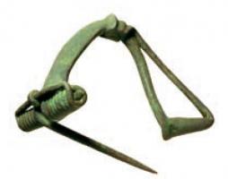 FIB-4578 - Fibule pseudo-La Tène II hybridebronzeForme hybride entre un type à plaquettes (arc plat, ressort à corde externe avec griffe) et un type pseudo-La Tène II pour le pied, replié vers l'arc et rattaché au sommet de ce dernier par une bague à moulures transversales.