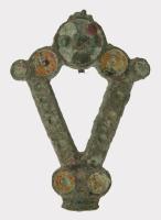 FIB-4814 - Fibule émailléebronzeFibule en forme de broche triangulaire, ajourée, constituée d'une simple bande émaillée, accostée de plusieurs disques émaillés. Au revers, articulation à charnière sur deux plaquettes.