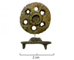 FIB-6114 - Fibule circulairebronzeFibule circulaire, avec des perforations autour d'un cabochon central pour émail ou pierre incrustée; bord profondément encoché; bélière rectangulaire pour la fixation du ressort, et porte-ardillon en crochet.