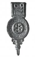 FRT-9015 - Ferret de ceinturebronzeTPQ : 1300 - TAQ : 1450Ferret à corps circulaire, avec une inscription en lettres gothiques autour d'un fleuron; sur la plaque de fixation, initiale gothique sur fond gaufré, deux rivets; lest à la base.