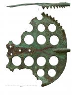 IND-9110 - MalaxeurbronzePièce technique, de forme circulaire, prolongée d'un côté par un ergot formant axe de rotation, tandis qu'à l'opposé un axe rapporté était solidement fixé par des rivets. L'objet, plat et épais, possède sur une partie de sa circonférence des dents perpendiculaires apparemment destinées à décoller un matériau pâteux (on observe un dispositif symétrique de l'autre côté), tandis que la surface est percée de plusieurs trous de diamètres différents.