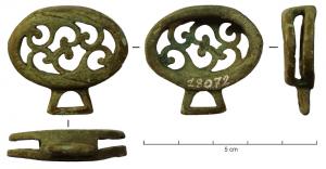 JHA-4035 - Passant de harnais avec suspensionbronzePassant de harnais de forme ovale, évidé dans l'épaisseur afin de permettre le passage d'une sangle horizontale; la face supérieure est ornée d'ajours de style végétal stylisé, et une bélière trapézoïdale, sous la pièce, pemettait la suspension d'un pendant.