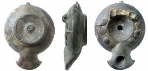 LMP-3013 - Lampe tournée fermée à décor pastillé Cnideterre cuiteLampe tournée fermée modelée, anse manquante constituée par deux boudins d'argile soudés reliés par un ou deux anneaux de terre, réservoir biconique, petit disque profond au petit trou d'alimentation, large bandeau au décor pastillé, large bec en bras d'ancre ; base en relief, striée, tournassée, globule central.