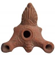 LMP-3126 - Lampe à bec multiplesterre cuiteLampe à deux becs allongés, à la partie supérieure décorée d’une palmette, et anse plastique en forme de feuille issue d’une volute, à l’arrière. Entre les becs, petit masque grimaçant. Large trou de remplissage central entouré de deux cercles en relief, autour desquels, sur l’épaule, des demi- oves sont imprimés. Base plate définie par un cercle incisé.