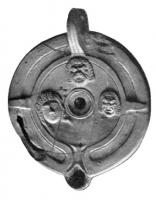 LMP-4042 - Lampe Loeschcke VIII : Masques de théâtreterre cuiteLampe à un bec rond; disque décoré de trois masques de théâtre; anse percée ; épaule nue. Cette lampe mérite d'être différenciée des autres car l'épaule est déjà traitée de façon novatrice (zones ovales creuses) et le bec n'est plus aussi mis en évidence. Seuls  subsistent du type traditionnel les ergots sur l'épaule.