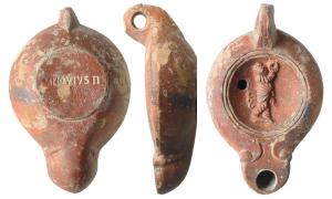LMP-41543 - Lampe Loesckcke V : Prêtre de Cybèle, M NOV IVSTIterre cuiteAnse percée à deux sillons, moulée avec la lampe; réservoir piriforme de profil biconvexe asymétrique; bandeau penché vers l'extérieur. Disque circulaire limité par deux sillons. Décor : prêtre de Cybèle jouant du tympanon, à droite. Bec long en ogive, à volutes simples se poursuivant sous le bec. Base circulaire limitée par un sillon estampillée M NOV IVSTI. Engobe rouge brique sur toute la lampe.  