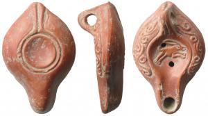 LMP-41665 - Lampe Hayes I : Lièvreterre cuiteLampe moulée, anse verticale percée à deux sillons, faisant avec la patère une excroissance caractéristique du type. Réservoir piriforme de profil biconvexe. Rinceaux en relief sur le bandeau encadrés par un sillon. Bec et disque  entourés par un bourrelet.: lièvre bondissant à droite sur le disque. Base concave limitée par deux gouttières concentriques formant une patère avec le double bourrelet rejoignant l'anse. Engobe rouge brique brillant.