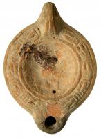 LMP-41859 - Lampe à bec cordiforme : Gladiateurterre cuiteMoulée, anse verticale pleine à deux sillons sur la tranche. Réservoir circulaire à profil biconvexe. Bandeau penché vers l'extérieur au décor de guirlande de laurier noué. Disque en simple cuvette limitée par deux sillons ; gladiateur à droite un genou à terre (?) mais décor très usé. Restes d'un clou de mèche. Bec arrondi cordiforme . 
