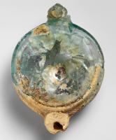 LMP-41972 - Lampe en verreverreLampe en verre naturel, ansée. Bec rond, saillant, avec trou de mèche ; corps circulaire avec les épaules légèrement concaves, séparées du disque par une cannelure ; disque plat, enfoncé au centre.